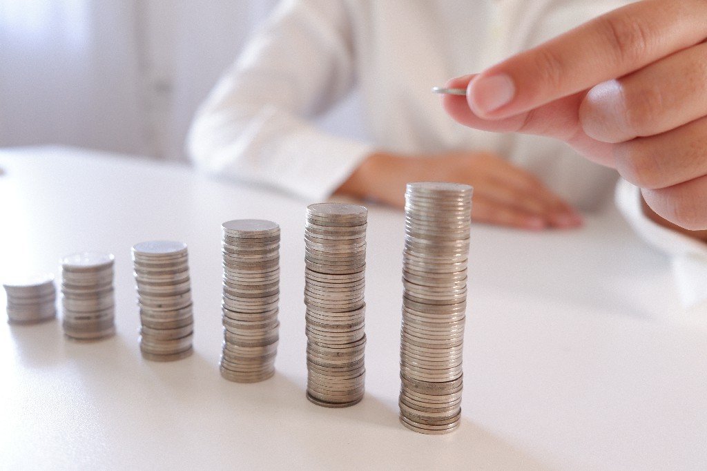 Business Person Placing Coin Over The Increasing Coins Stack